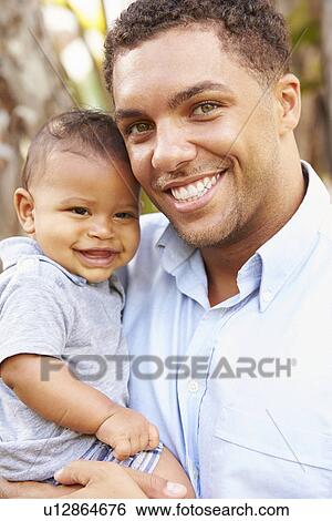 Portrait Of Smiling Father Holding Baby Son Outdoors View Large Photo Image Stock Photograph - Portrait Of Smiling Father Holding Baby Son Outdoors. Fotosearch