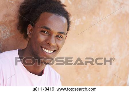 Stock Photo - Portrait Of Smiling Man Leaning Against Wall. Fotosearch