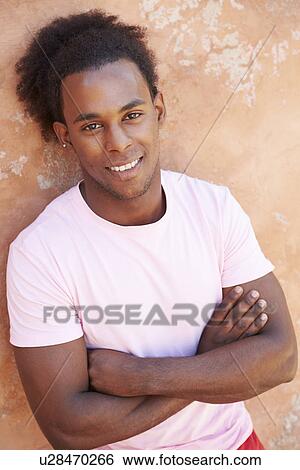 Stock Photograph - Portrait Of Smiling Man Leaning Against Wall. Fotosearch