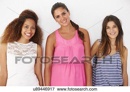 Stock Photo - Portrait Of Three Female Friends Leaning Against Wall. Fotosearch