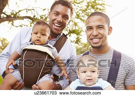 Stock Image - Portrait Of Two Fathers With Baby Carriers In Park. Fotosearch