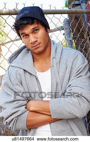 Portrait Of Young Man In Urban Setting Standing By Fence View Large Photo Image Picture - Portrait Of Young Man In Urban Setting Standing By Fence. Fotosearch