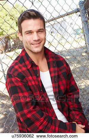 Portrait Of Young Man In Urban Setting Standing By Fence View Large Photo Image Stock Image - Portrait Of Young Man In Urban Setting Standing By Fence. Fotosearch