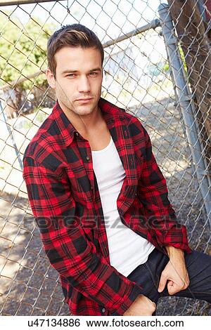 Portrait Of Young Man In Urban Setting Standing By Fence View Large Photo Image Stock Photograph - Portrait Of Young Man In Urban Setting Standing By Fence. Fotosearch