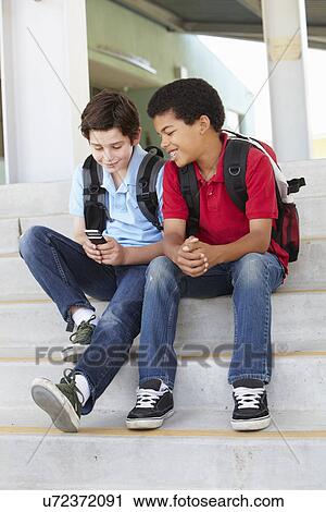 Stock Image - Pre teen boys with phone at school. Fotosearch