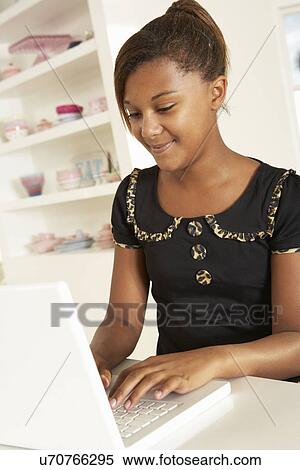 Stock Photography - Pre-teen girl working on laptop at home. Fotosearch