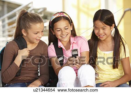 Picture - Pre teen girls in school with cellphone. Fotosearch