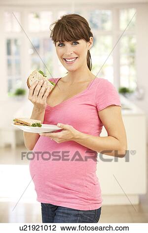 Stock Image - Pregnant woman eating sandwich. Fotosearch