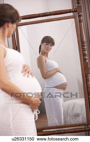 Pregnant woman looking in mirror View Large Photo Image Stock Image - Pregnant woman looking in mirror. Fotosearch