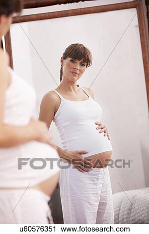 Pregnant woman looking in mirror View Large Photo Image Stock Image - Pregnant woman looking in mirror. Fotosearch