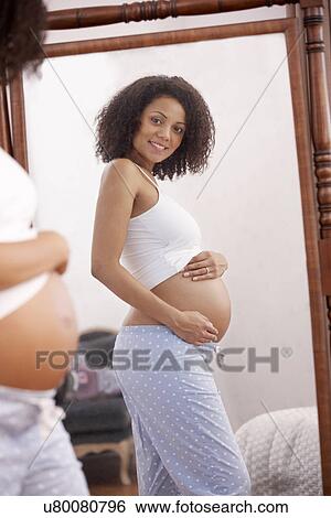 Pregnant woman looking in mirror View Large Photo Image Stock Photograph - Pregnant woman looking in mirror. Fotosearch