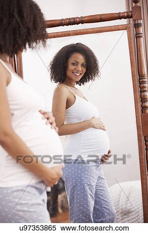 Stock Photography - Pregnant woman looking in mirror. Fotosearch