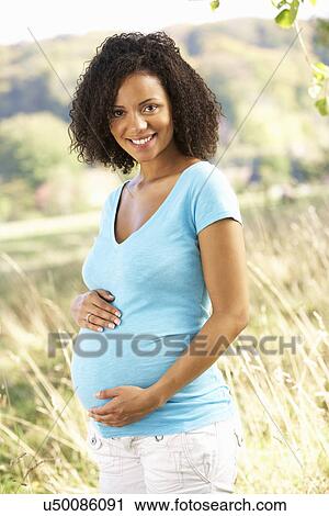 Stock Image - Pregnant woman outdoors in countryside. Fotosearch