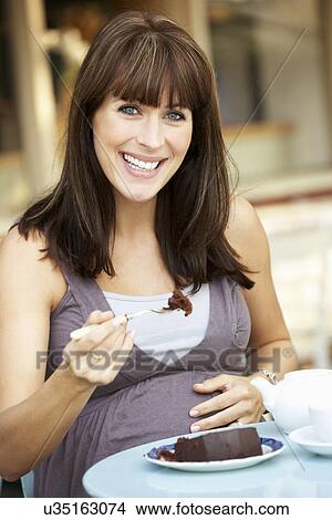 Picture - Pregnant woman sitting outside café. Fotosearch