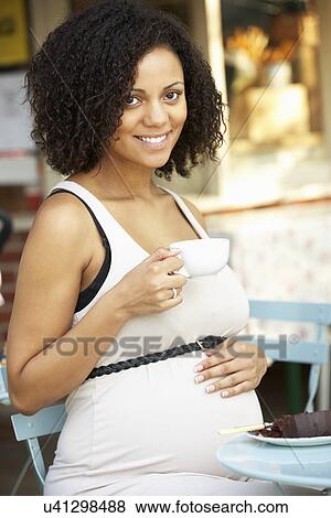 Stock Photo - Pregnant woman sitting outside café. Fotosearch