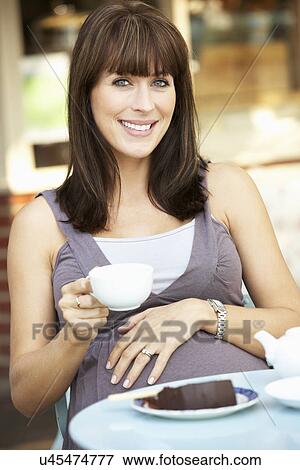 Stock Photo - Pregnant woman sitting outside café. Fotosearch