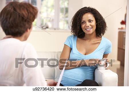 Stock Image - Pregnant woman talking to midwife. Fotosearch