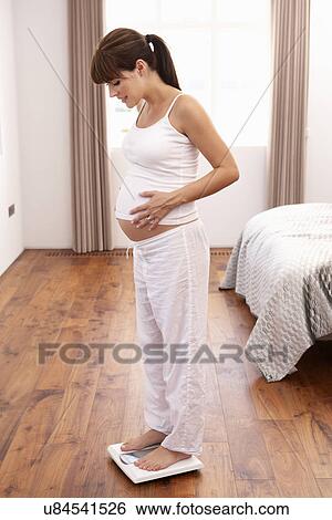 Pregnant woman weighing herself View Large Photo Image Stock Photograph - Pregnant woman weighing herself. Fotosearch