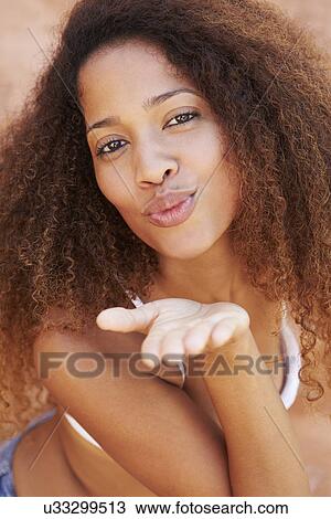 Stock Image - Pretty Young Woman Blowing Kiss Towards Camera. Fotosearch