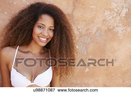 Stock Photo - Pretty Young Woman Wearing Swimsuit Leaning Against Wall. Fotosearch