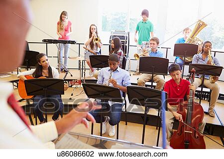 Stock Image - Pupils Playing Musical Instruments In School Orchestra. Fotosearch