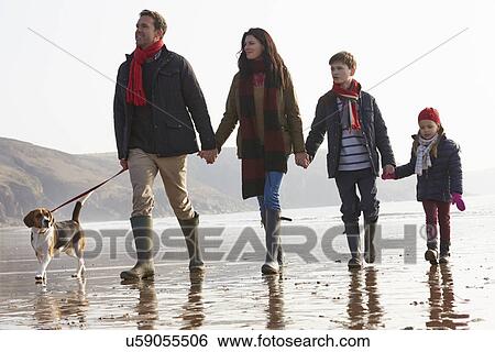 Stock Photograph - Rear View Of Family Walking Along Winter Beach With Dog. Fotosearch