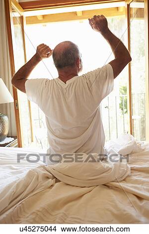 Picture - Rear View Of Man Waking Up In Bed In Morning. Fotosearch