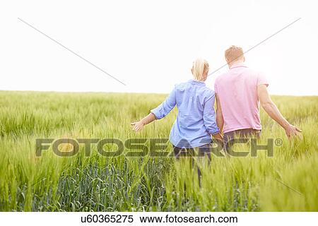 Rear View Of Romantic Couple Walking In Field Holding Hands View Large Photo Image Stock Photography - Rear View Of Romantic Couple Walking In Field Holding Hands. Fotosearch