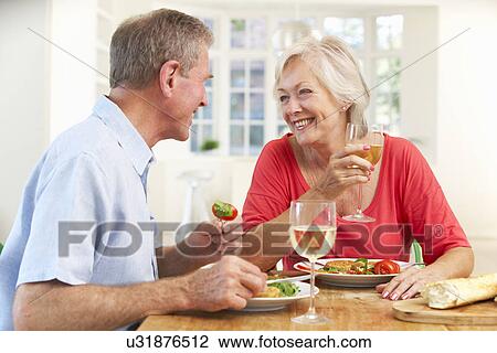 Stock Image - Retired couple enjoying meal at home. Fotosearch