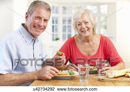 Stock Image - Retired couple enjoying meal at home. Fotosearch