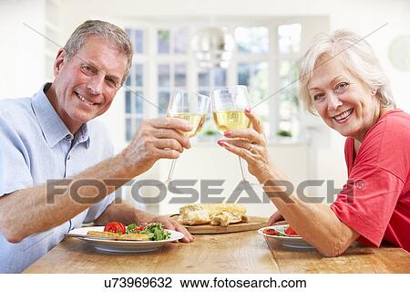 Stock Image - Retired couple enjoying meal at home. Fotosearch