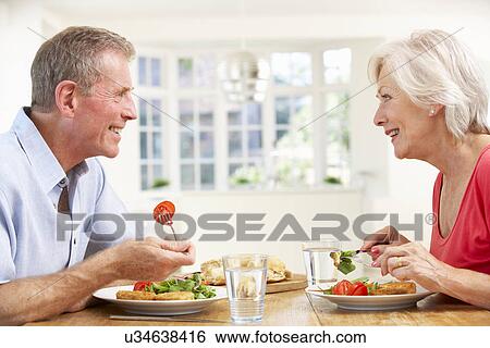 Stock Photograph - Retired couple enjoying meal at home. Fotosearch