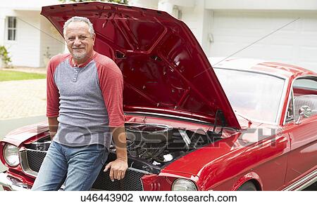 Stock Image - Retired Senior Man Working On Restored Classic Car. Fotosearch