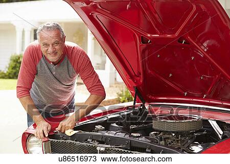 Stock Image - Retired Senior Man Working On Restored Classic Car. Fotosearch
