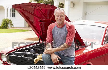 Stock Photo - Retired Senior Man Working On Restored Classic Car. Fotosearch