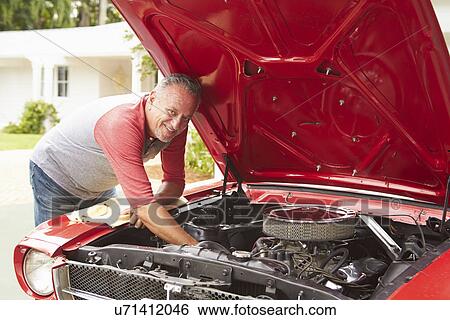 Stock Photograph - Retired Senior Man Working On Restored Classic Car. Fotosearch