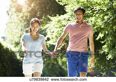 Stock Image - Romantic Asian Couple On Walk In Countryside. Fotosearch