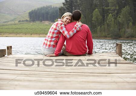 Picture - Romantic couple sitting on a jetty. Fotosearch