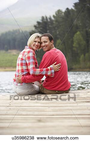 Romantic couple sitting on a jetty View Large Photo Image Stock Photo - Romantic couple sitting on a jetty. Fotosearch