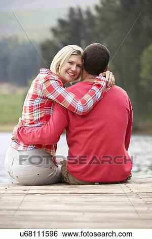 Romantic couple sitting on a jetty View Large Photo Image Stock Photograph - Romantic couple sitting on a jetty. Fotosearch