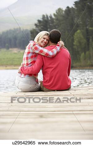 Stock Photography - Romantic couple sitting on a jetty. Fotosearch