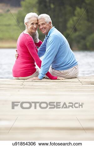 Romantic senior couple sitting on a jetty View Large Photo Image Stock Photograph - Romantic senior couple sitting on a jetty. Fotosearch