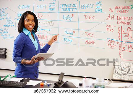 Stock Image - Science Teacher Standing At Whiteboard With Digital Tablet. Fotosearch