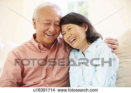 Senior Asian Couple Sitting On Sofa At Home Together View Large Photo Image Picture - Senior Asian Couple Sitting On Sofa At Home Together. Fotosearch
