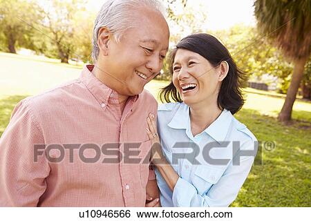 Stock Photograph - Senior Asian Couple Walking Through Park Together. Fotosearch