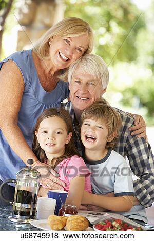 Senior couple and grandchildren eating breakfast outdoors View Large Photo Image Stock Photo - Senior couple and grandchildren eating breakfast outdoors. Fotosearch