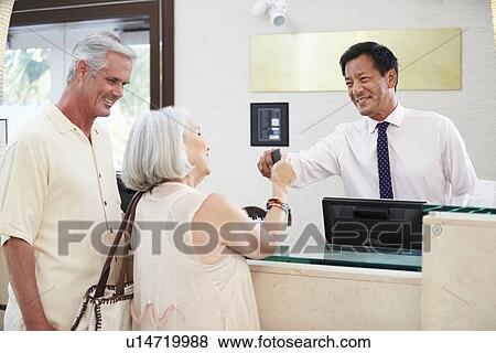 Senior Couple Checking In At Hotel Reception View Large Photo Image Stock Photo - Senior Couple Checking In At Hotel Reception. Fotosearch