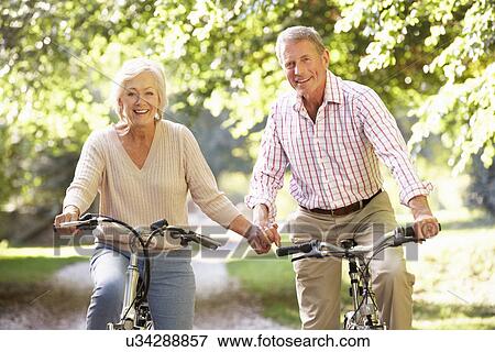 Stock Photo - Senior couple cycling in park. Fotosearch