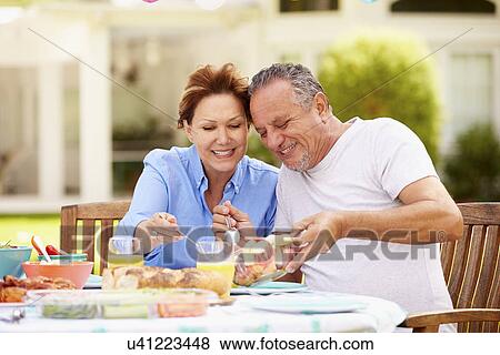 Senior Couple Enjoying Meal In Garden Together View Large Photo Image Stock Photo - Senior Couple Enjoying Meal In Garden Together. Fotosearch