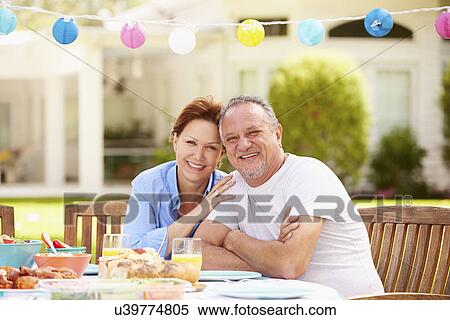 Stock Photography - Senior Couple Enjoying Meal In Garden Together. Fotosearch